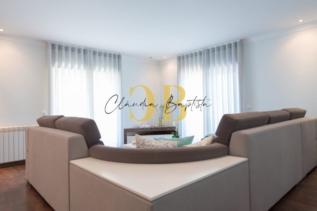 Sala com sofá e cortinados de ondas cinzentos nas janelas
