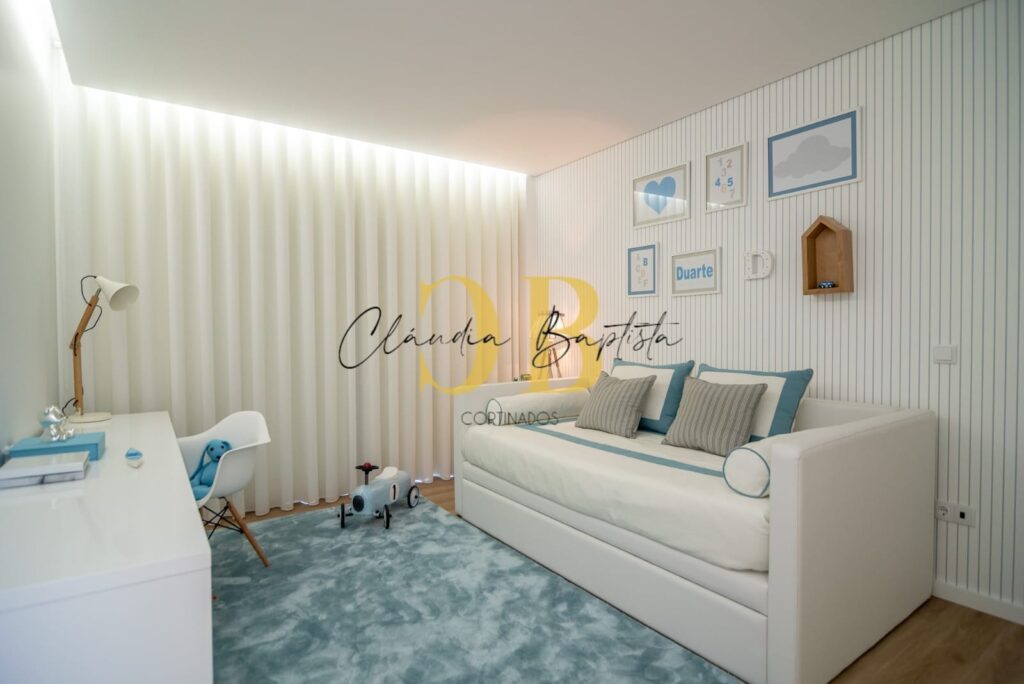 Quarto de criança com sofá-cama e cortinados de ondas brancos, com luz indireta